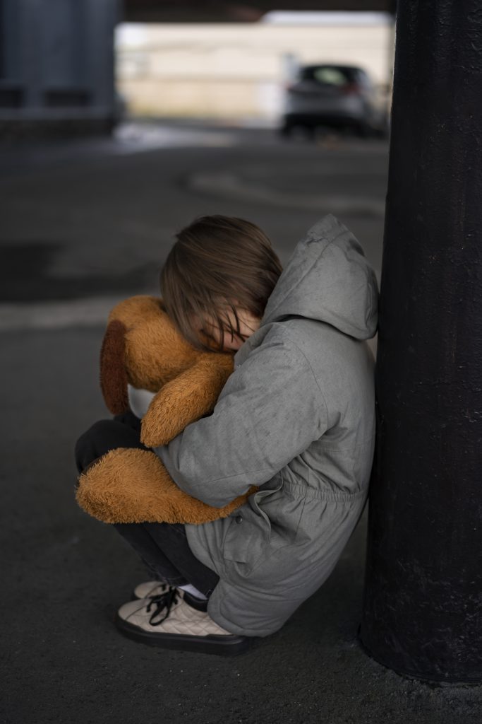 Niña solitaria que se aferra a su peluche simbolizando el abandono