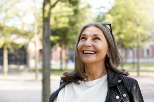 Mujer madura sonriendo con expresión segura, vestida con chaqueta de cuero moderna, simbolizando aceptación y disfrute de su etapa vital con estilo y autenticidad.
